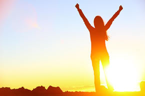 woman raising arms in sunlight